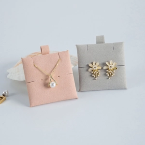 Pink and grey velvet jewelry display pads showing pearl necklaces and flower earrings