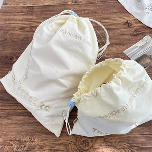 Detail view of cream drawstring organizer bags with blue cord locks on a wooden desk