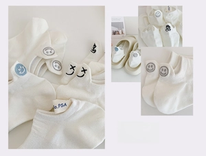 Detail of white cotton no-show socks with embroidered smile and KAWS-style eyes on the heel