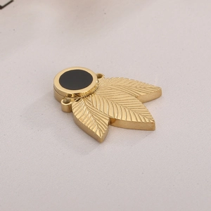Macro shot of gold clover-shaped stainless steel jewelry pendant with black circular detail