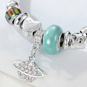 Macro shot of silver-plated heart charm with Be my Valentine text and saturn planet pendant