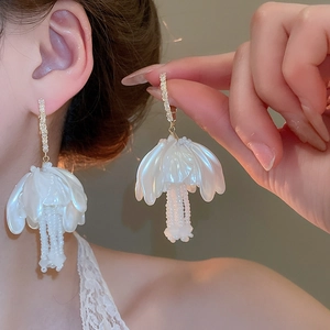 Detail of white flower tassel earrings with pearl beads and sparkling crystal studs