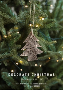Detail of wooden Christmas tree ornament made of natural cedar bark hanging on a pine branch