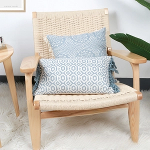 Blue bohemian pillowcases with ethnic patterns and fringe tassels on a woven chair