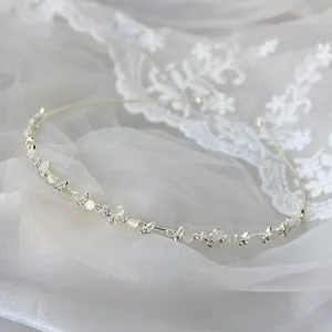 Dettaglio del cerchietto d'argento con farfalle e strass su sfondo di pizzo bianco
