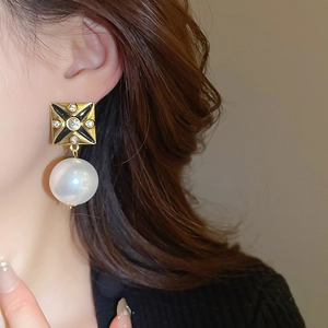 Close-up of vintage square black gold earring with rhinestones and a white drop pearl