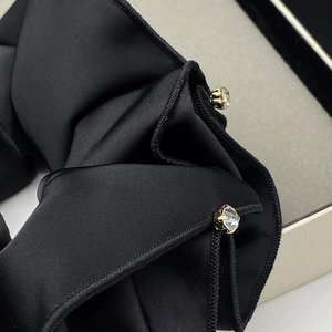 Macro shot of black satin scrunchie featuring elegant rhinestone details and premium texture