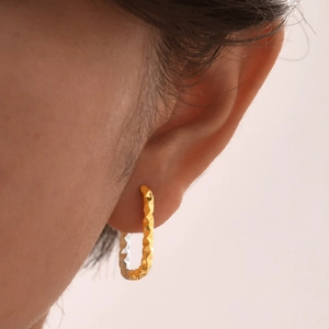 Detailed macro view of U-shaped earrings with textured surface and dual-tone finish