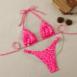 Flat lay of pink leopard print bikini set with golden sun buckle and summer accessories