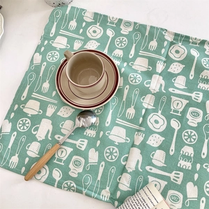 Détail macro du set de table en coton vert avec motifs de cuisine blancs dessinés