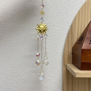 Detail of golden suncatcher with smiling sun mask and faceted iridescent crystal balls