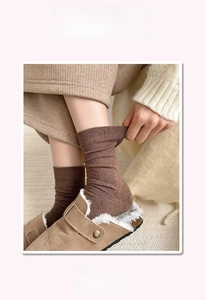 Close-up of ribbed dark coffee cotton socks paired with brown cozy sherpa-lined clogs