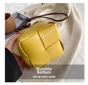 Close-up of yellow woven leather mini bucket bag with a slim brown shoulder strap