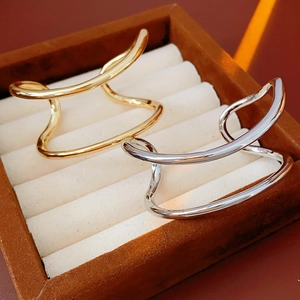 Détail de bracelets ouverts double couche irréguliers dorés et argentés sur un plateau