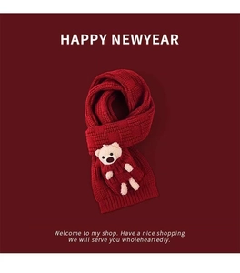 Close-up of the red knitted scarf with a cute beige plush bear doll and festive textures