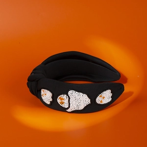 Detail of beaded pumpkin patterns on a black wide knotted fabric headband for Halloween