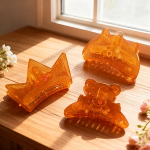 Three-piece amber orange resin hair clips with glitter and snowflake pattern