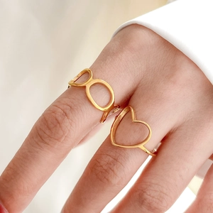 Close-up of golden openwork heart and geometric oval rings worn on fingers