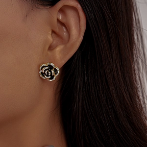 Close-up of black oil-dripping rose earrings with gold edges and inlaid rhinestones