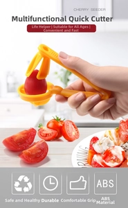 Close-up of a yellow cherry pitter slicing small fruits on a kitchen counter