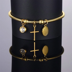 Golden Virgin Mary bracelet with cross charm and crystal on black reflective display