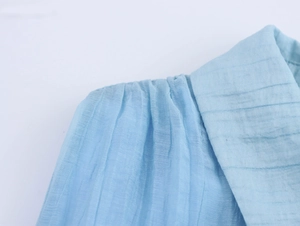 Detail view of light blue sleeveless dress showing vertical pleated texture and collar