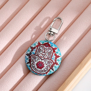 Bohemian Hamsa Hand and Om symbol round keychain with blue mandala pattern on display box