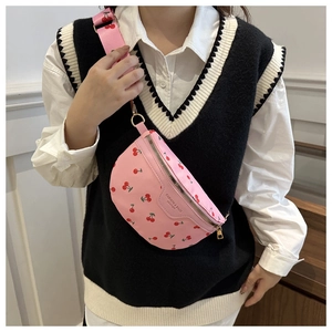 Close-up of pink cherry print canvas crossbody bag with wide strap on a female model