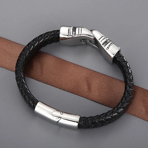 Detailed view of black braided leather bracelet with silver metal clasp on silk ribbon