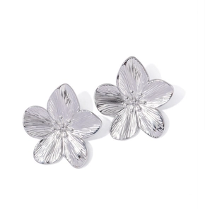 Detail showing high-polish silver flower earrings with fine brushed metal texture