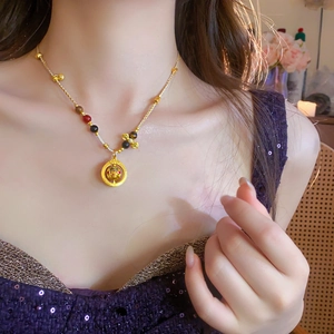 Close-up of a hollow circular pendant necklace with red and black beads on collarbone