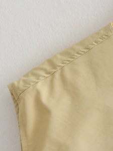 Gros plan détaillé des coutures doubles et du tissu beige lisse sur une veste à plis
