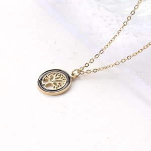Close-up of a Tree of Life pendant in gold and silver finish on a marble surface