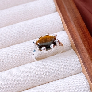 Macro view of vintage 18K gold plated ring with oval tiger eye stone and blue zircons