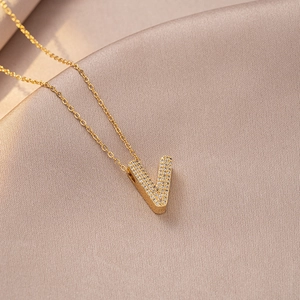 Macro shot of gold V-letter pendant necklace with sparkling white zircon stones