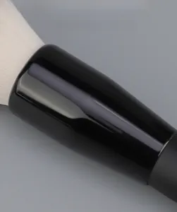 Détail macro du tube en aluminium épais et des poils synthétiques du pinceau à maquillage