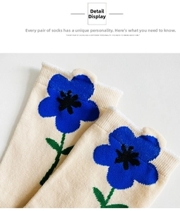 Close-up of knit crew socks featuring large blue floral patterns on creamy beige fabric