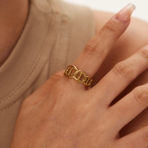 Detail of 18K gold-plated anchor chain ring on finger with polished glossy metallic finish