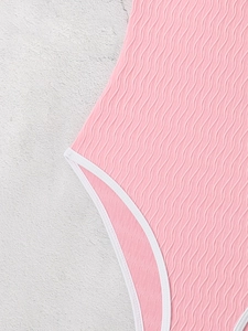 Close-up of pink swimsuit with wavy texture fabric and white elastic trim details