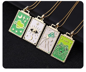 Macro shot of four tarot style necklaces with unique geometric patterns on dark background