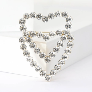 Elegant gold hollow heart brooch with clear rhinestones on white geometric stand
