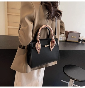 Détail d'un sac à main en cuir noir avec poignée en soie et boucle dorée élégante
