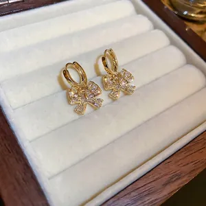 Elegant gold plated bow earrings with shimmering cubic zirconia stones on soft velvet background