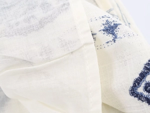 Detailed macro view of the cream cotton linen fabric with blue floral embroidery