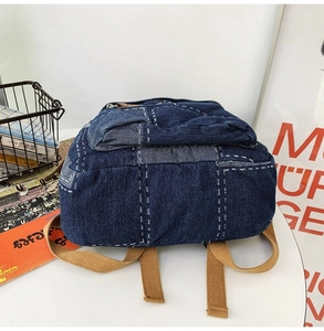 Detail of vintage patchwork denim backpack featuring contrast stitching and canvas straps
