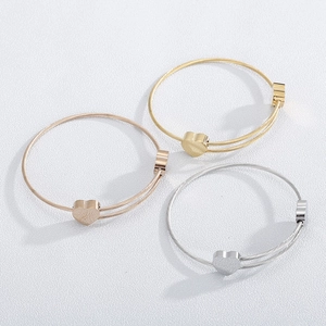 Detailed view of three-piece heart cable bracelets in gold, silver, and rose gold finish