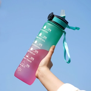 32oz green and pink gradient sports water bottle held against the blue sky background