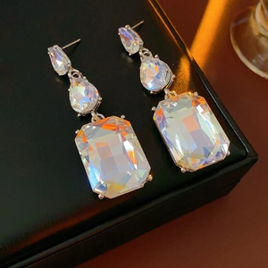Close-up of silver tassel earrings with iridescent crystal drops and square stones