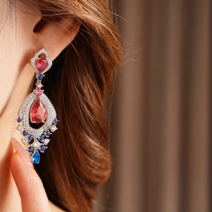 Detail of vintage teardrop earrings with red and blue zircon gems on model