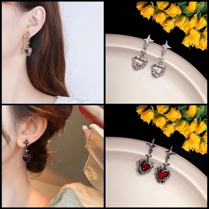 Detail view of heart star earrings in silver and dark red zirconia on a model